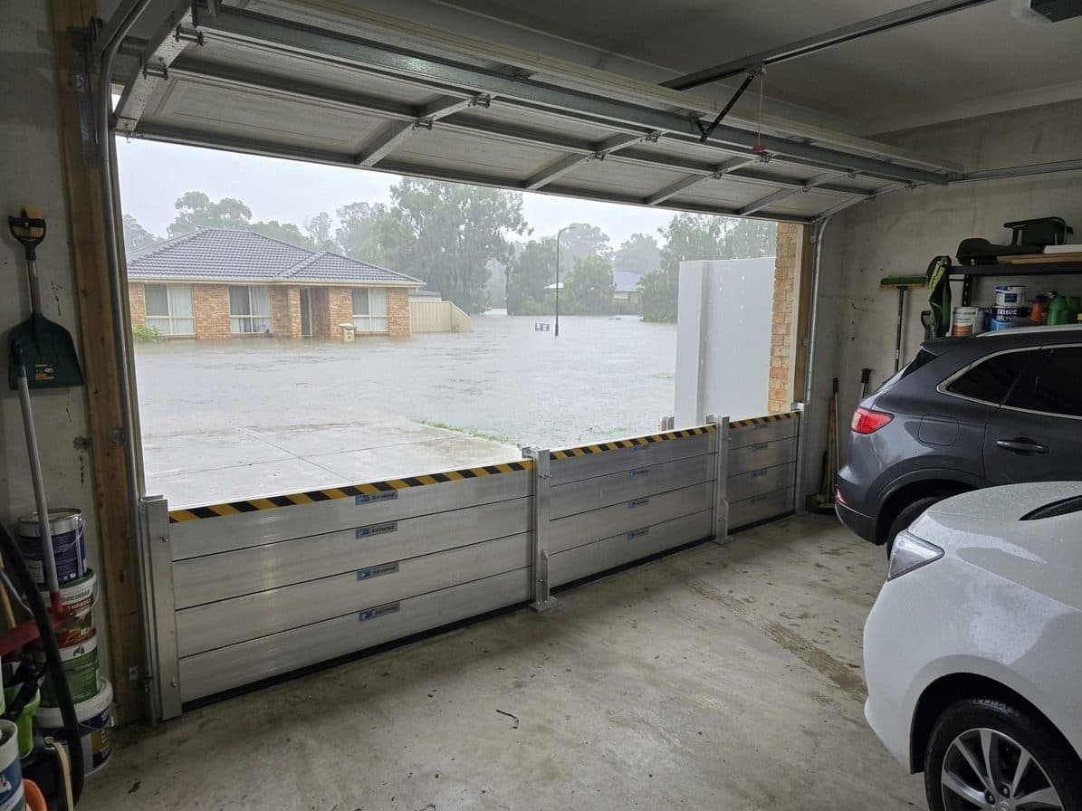 Flood barrier deployed across a double garage roller door in heavy rain