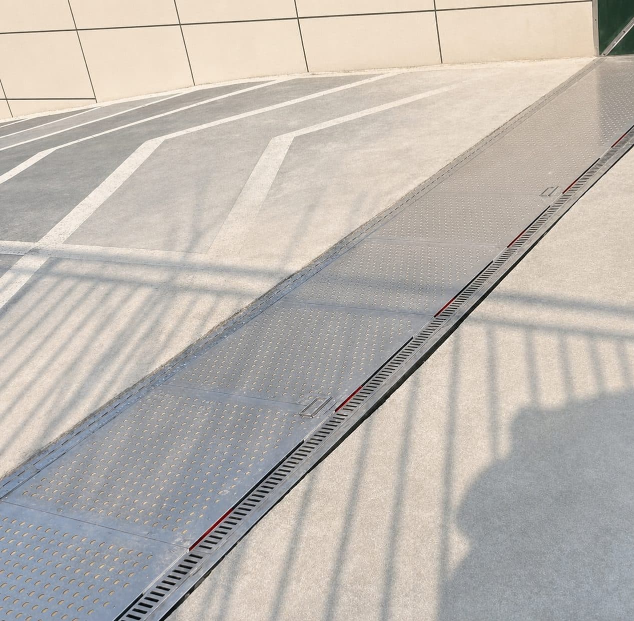 Hydrodynamic passive flood barrier sitting flush across a roadway entry during dry conditions