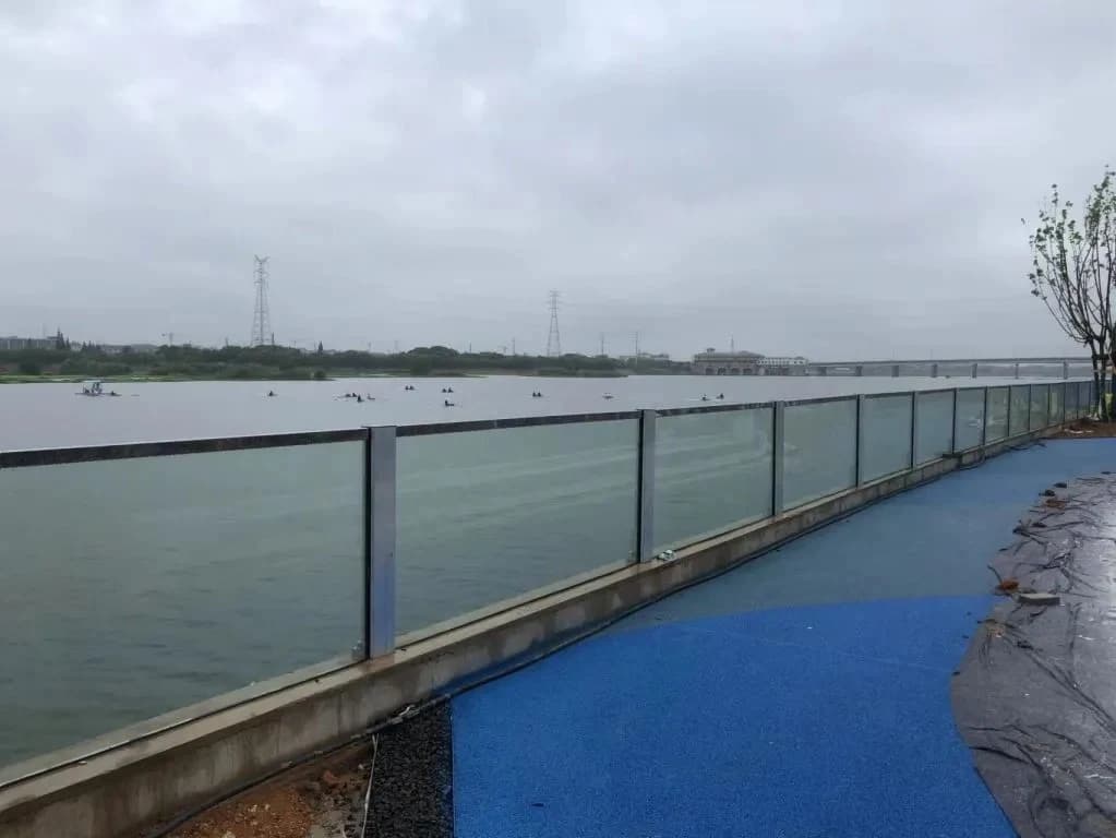 Glass flood wall on a concrete lakeside edge beside a cycle path