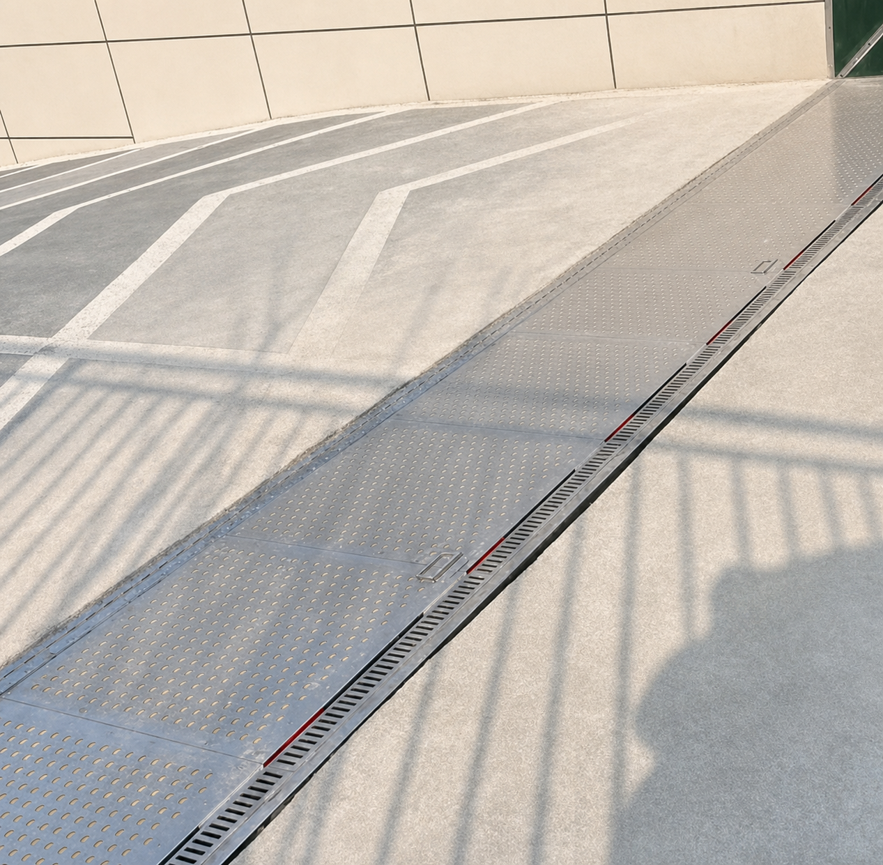 Hydrodynamic passive flood barrier sitting flush across a roadway entry during dry conditions