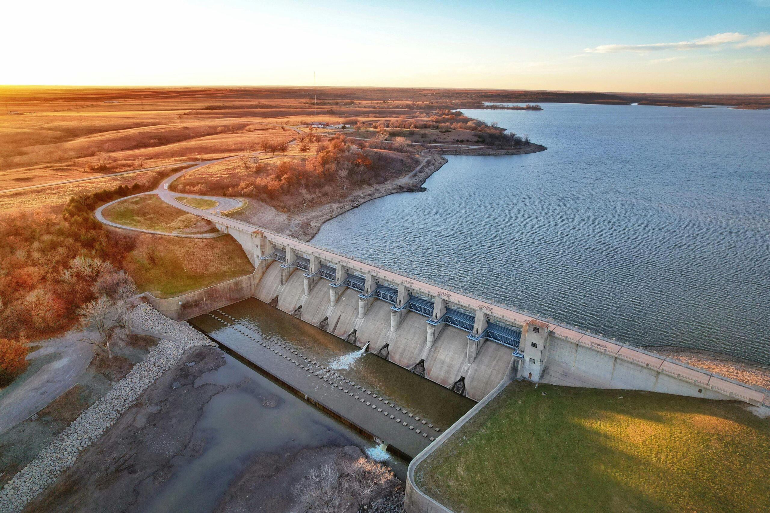 A scenic aerial view of a dam in Kansas, USA, at sunset with expansive lake and landscape.
